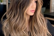 volumetric and wavy long brunette hair with blonde highlights and face-framing ones, with a lot of volume and waves