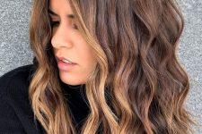 volumetric medium-length dark brunette hair with caramel highlights including face-framing ones, with waves