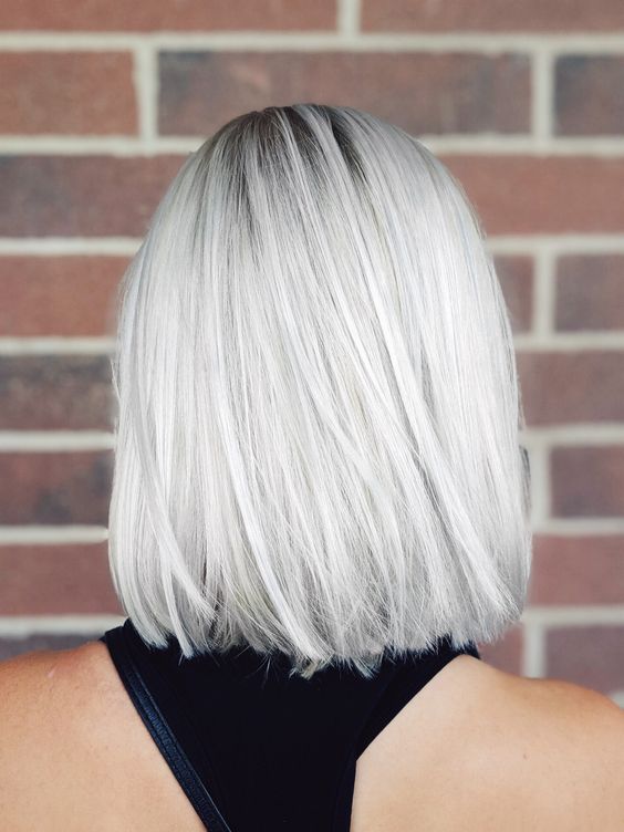 a silver blonde long straight bob with a darker root, a lot of volume, looks very bold, fresh and up-to-date