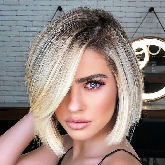A stylish and chic rooty blonde bob with side bangs and a lot of volume looks very eye catching and cool
