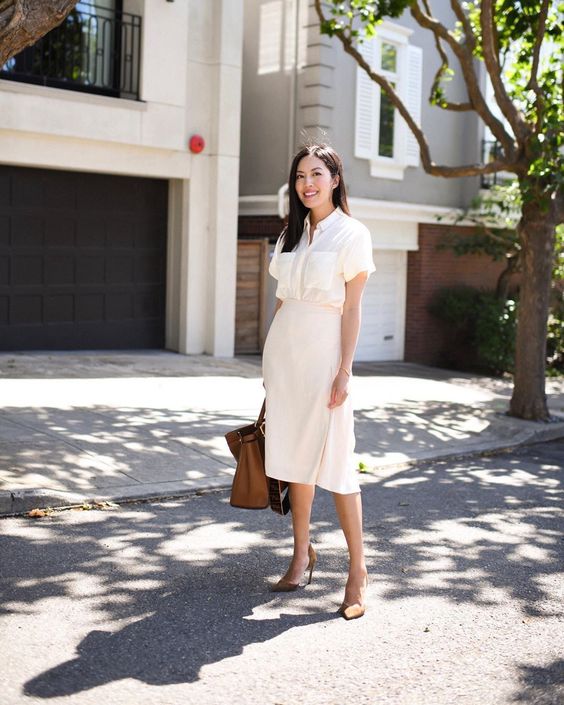 a white short sleeve shirt with pockets, a neutral wrap midi skirt, brown shoes and a brown bag