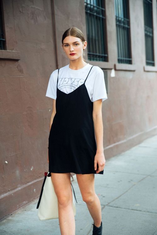 a white t-shirt, a black slip mini dress, black boots and a creamy tote for a spring or summer look