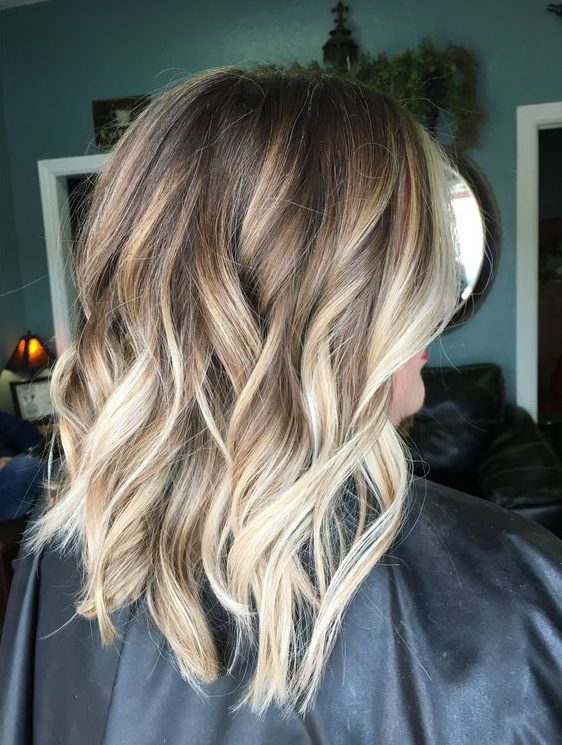 light brown wavy and layered hair with blonde balayage looks chic and very stylish