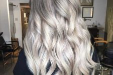 long hair with ashy roots and silver blonde balayage, with volume and waves is an eye-catching and cool idea