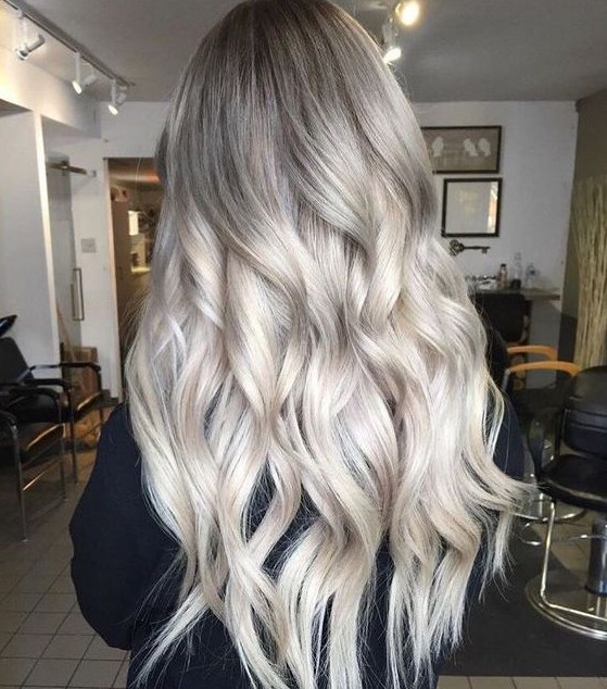 long hair with ashy roots and silver blonde balayage, with volume and waves is an eye-catching and cool idea