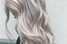 long silver blonde hair with a darker root, volume and waves is a chic and stylish idea for anyone