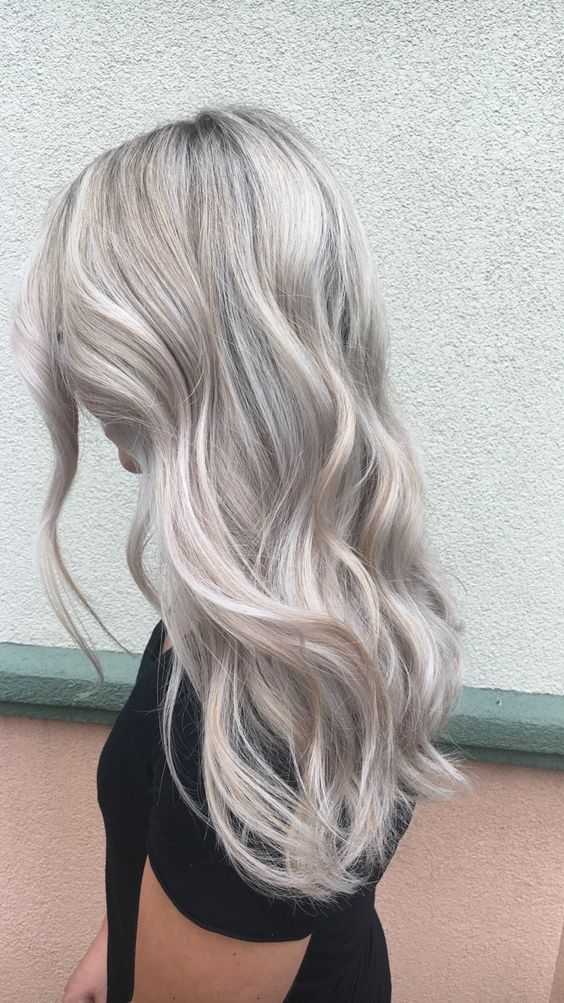 long silver blonde hair with a darker root, volume and waves is a chic and stylish idea for anyone