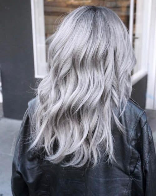 Long silver blonde to ashy grey hair, with volume and waves, is a stylish and eye catching idea to try