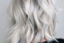 lovely medium-length silver blonde hair with a black root, messy waves and volume is a chic idea for today