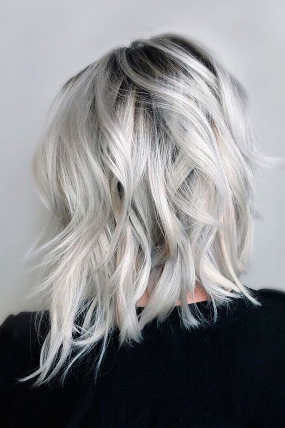 Lovely medium length silver blonde hair with a black root, messy waves and volume is a chic idea for today