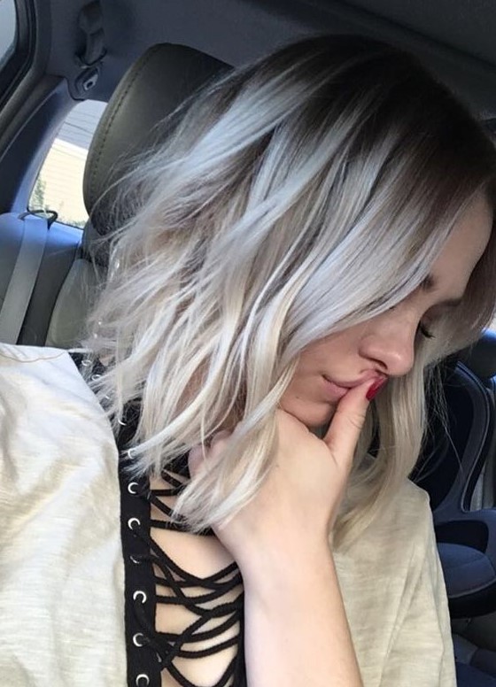 Medium length hair with darker root, silver blonde balayage and messy waves is a chic and cool idea