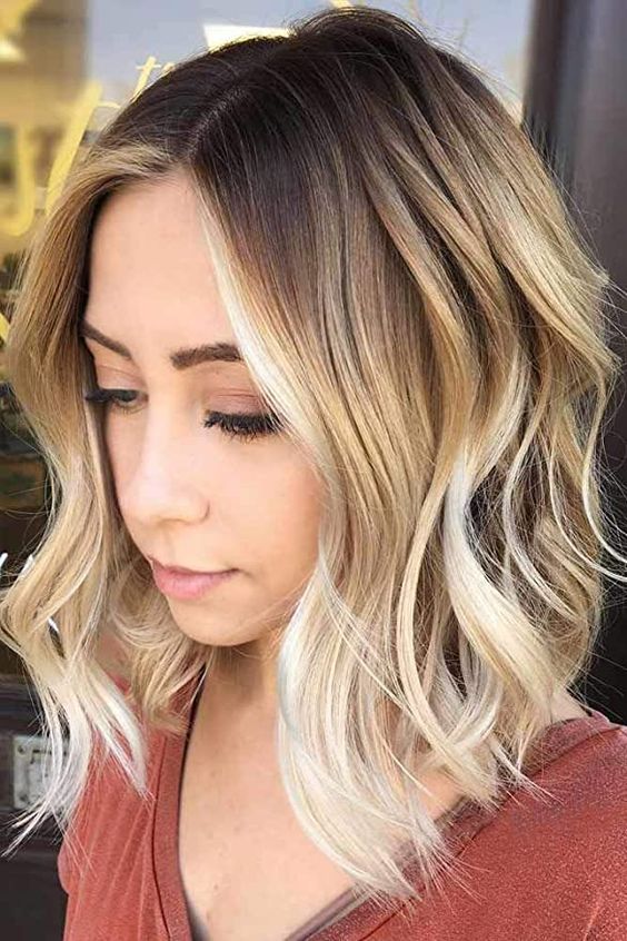 medium-length rooty blonde hair with bleached touches and waves looks very bold and catchy