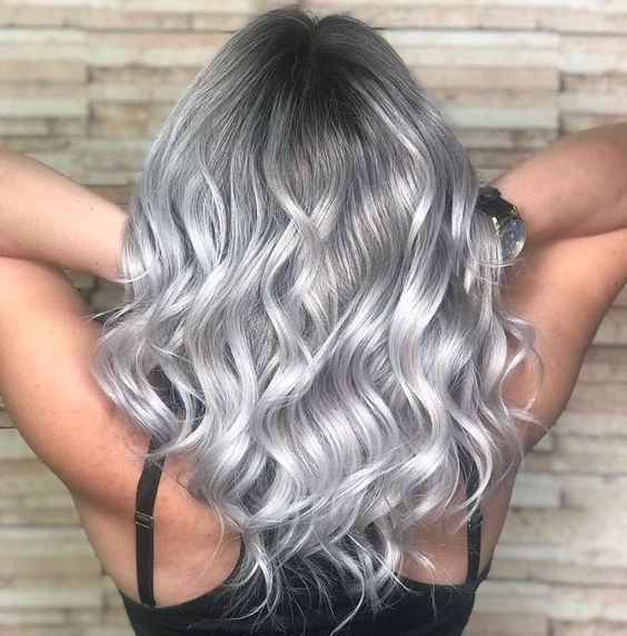 medium-length silver blonde hair with a darker root, waves down, is a chic and eye-catching idea to rock