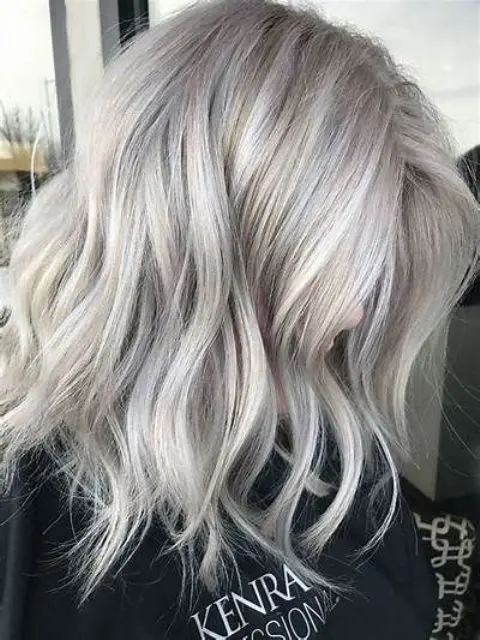 Medium length silver blonde hair with volume and messy waves is a stylish idea, and the edgy shade inspires