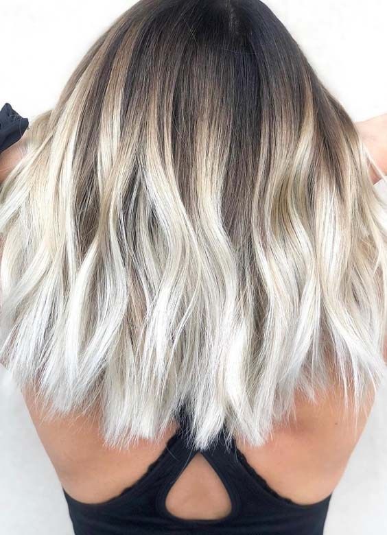 Meidum length silver blonde hair with a darker root and mesys waves is a stylish and catchy idea