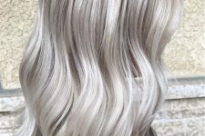 shoulder-length silver blonde hair with a darker root, waves and volume is a stylish and chic idea, it looks bold
