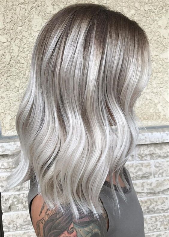 shoulder-length silver blonde hair with a darker root, waves and volume is a stylish and chic idea, it looks bold
