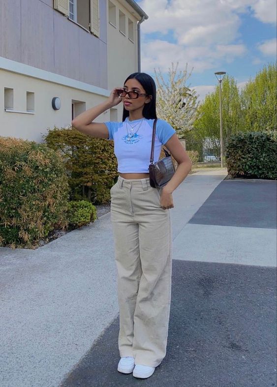 a 90s inspired look with a color block cropped tee, tan high waisted pants, white trainers and a baguette bag