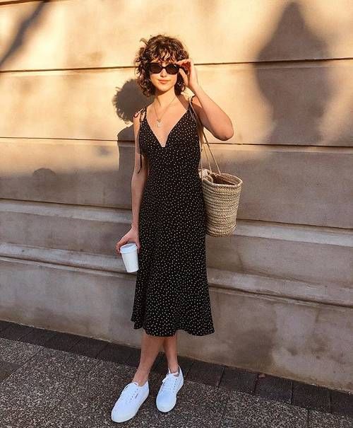 a black polka dot midi dress with bows on the shoulders, white sneakers, a straw bag for a casual summer date