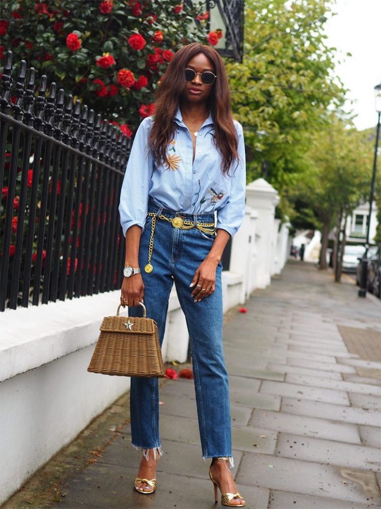 a blue floral embroidered shirt, blue jeans, a gold chain belt, gold heels and a straw bag