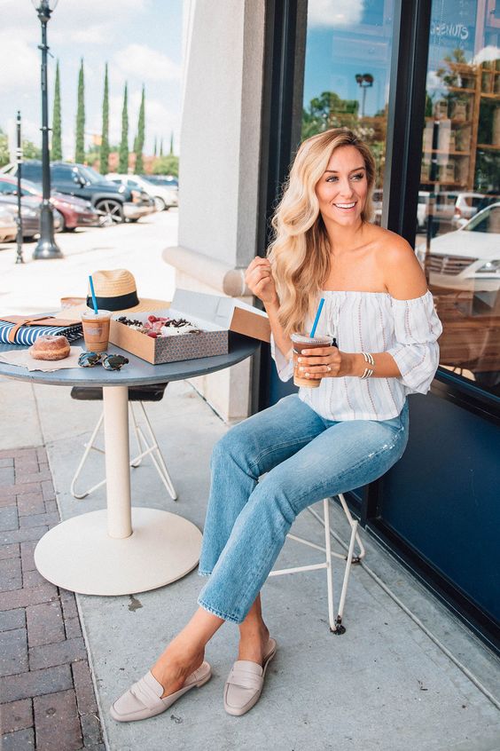 a blue striped off the shoulder top, blue cropped jeans, grey slipper mules and a hat for a summer coffee date