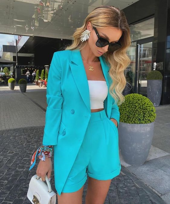 a bright suit with an oversized blazer and shorts, a white bandeau top, a white mini bag and statement earrings