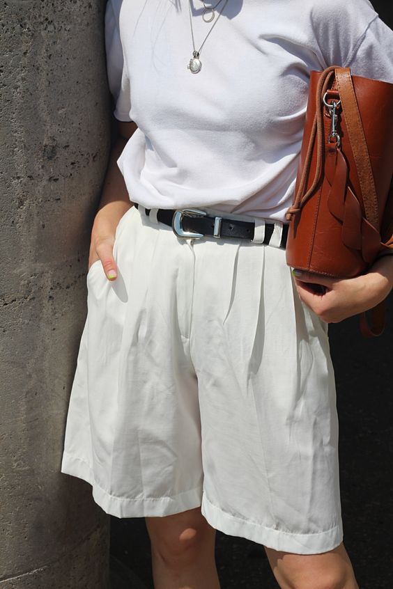 a classic look with a white t-shirt, white bermuda shorts, a black belt and a brown bag