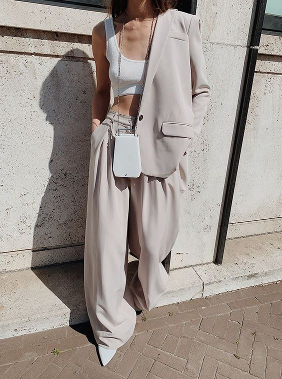 a dove grey oversized pantsuit, a white bra top, a white bag and heels for spring or summer