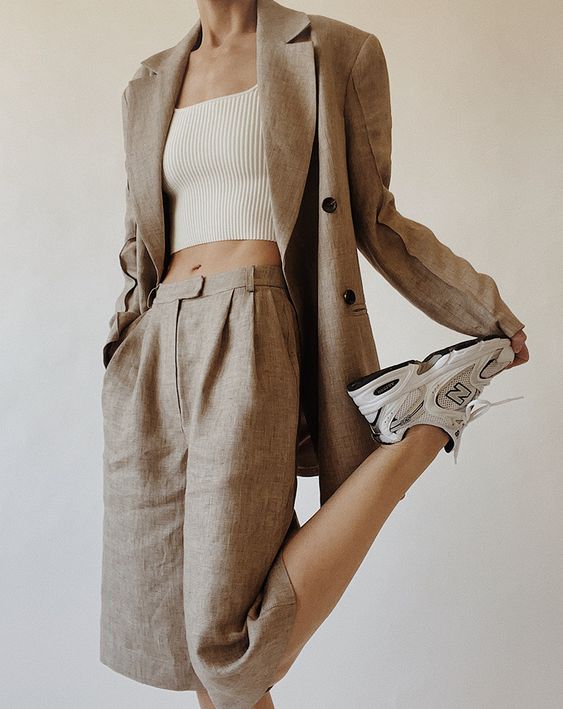 a grey linen short suit with Bermuda shorts, an oversized blazer, white trainers and a white crop top for work