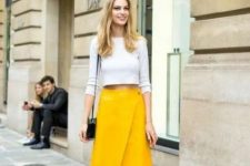 a grey long sleeve crop top, a yellow wrap asymmetrical skirt, black lacquer strap sandals and a black bag