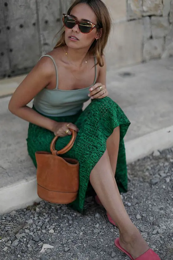 a light green spaghetti strap top, an emerald midi skirt, pink mules and a brown bucket bag