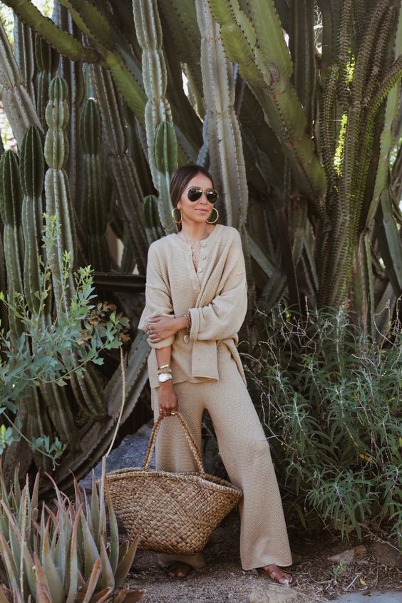a neutral linen suit with a button up shirt and wideleg pants, sandals, a straw bag and statement accessories