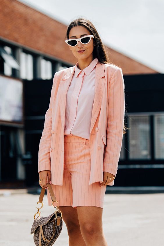 a peachy pink striped short suit, a pink shirt, a baguette bag and trendy retro sunglasses