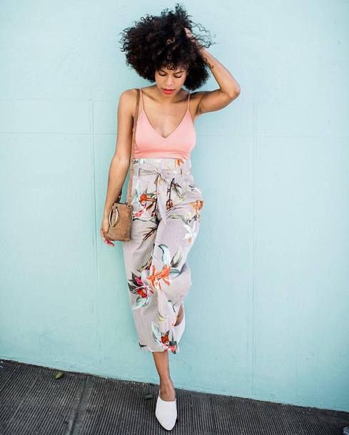 a pink spaghetti strap top with a depe neckline, bright floral printed cropped pants, white mules and a brown bag