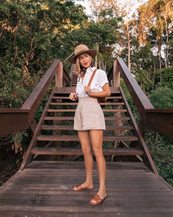 a pretty look with a white shirt, grey high waisted shorts, brown slippers, a hat and a backspack