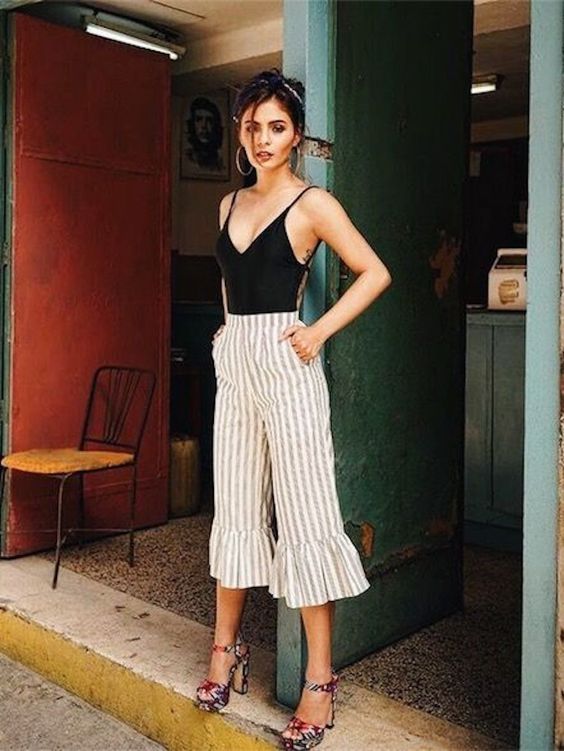 a retro inspired look with a black bodysuit, striped flare pants, colorful platform heels