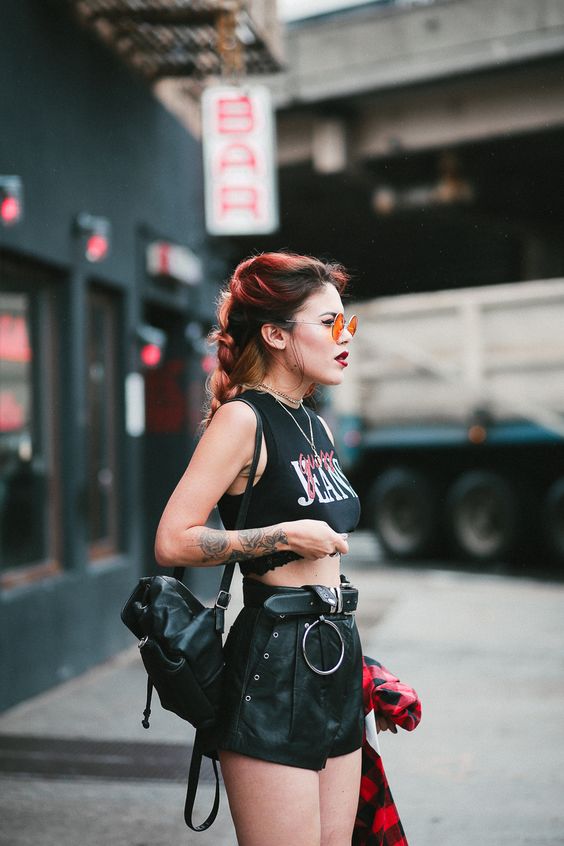 a rock style look with a cropped t-shirt, black elather shorts, a black belt and a backpack