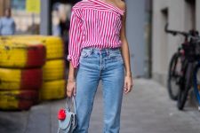 a striped one shoulder shirt, blue cropped jeans, white shoes and a blue bag with a fluff