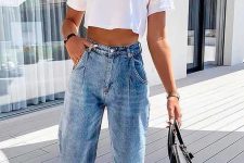 a white cropped t-shirt, blue barrel jeans, white sneakers and a black bag for a casual look