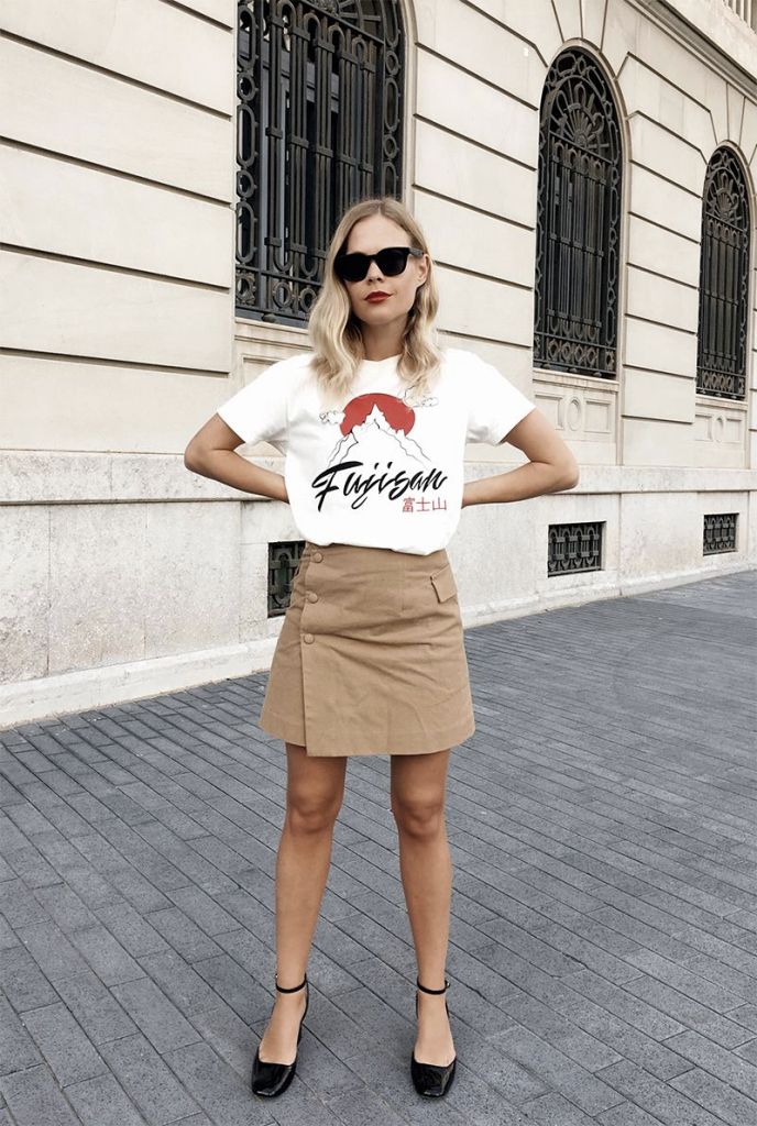 a white printed t shirt, a tan button up mini skirt, black square toe shoes for a simple and bold look