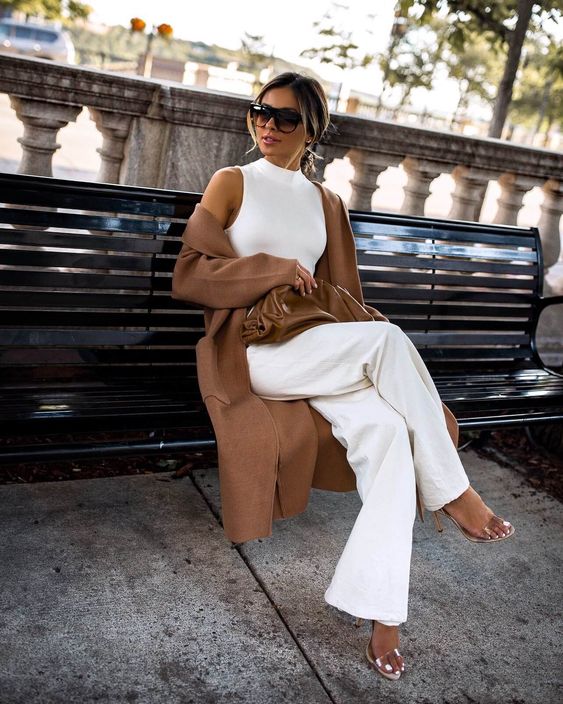 a white sleeveless halter neckline top, wideleg pants, silver shoes, a brown clutch and a duster