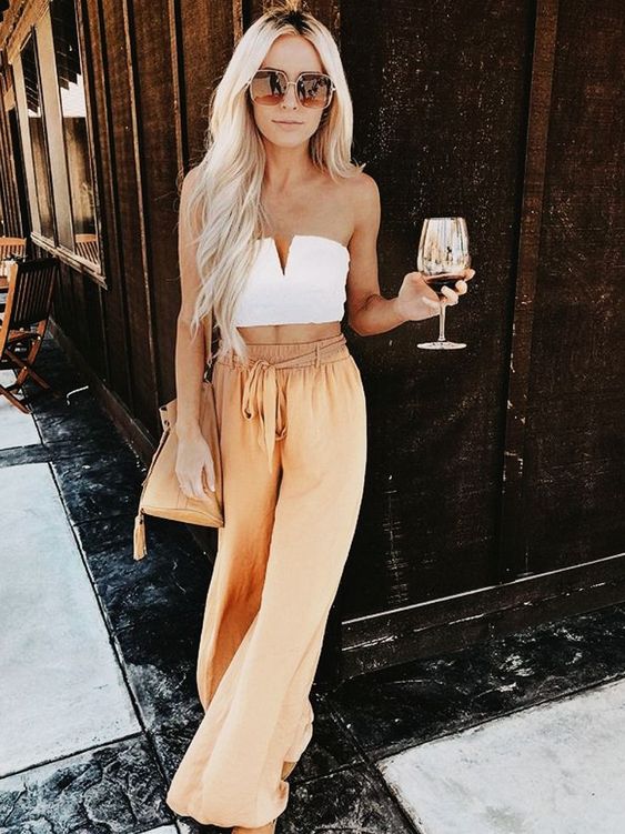 a white strapless crop top, yellow linen wideleg pants, a tan bag and sunglasses for a summer brunch