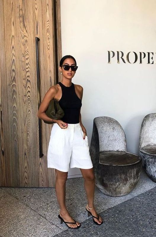 an ultra-minimalist look with a black halter neckline top, white bermuda shorts, black heels and a clutch