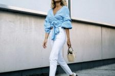 white jeans, a blue gingham wrap crop blouse with puff sleeves, white perforated shoes and a straw bag