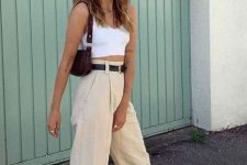 22 a white crop top, tan high waisted pants, black belts, white trainers, a brown baguette bag for summer