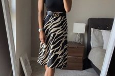 a black halter neckline top, a black printed A-line skirt with a belt, black heels for a sleek and chic look