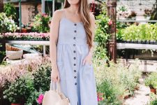a blue linen midi dress with pockets and buttons, brown slippers, a hat and a round woven bag for a hot summer day