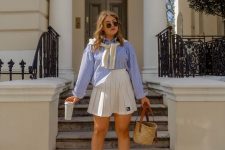 a blue striped shirt, a white high waisted pleated mini, white socks and trainers plus a straw bag for a comfy look