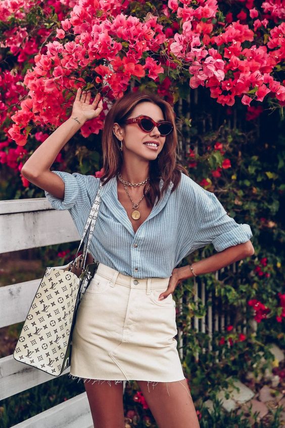 a casual summer look with a blue striped linen shirt, a neutral denim mini, a printed tote and layered necklaces