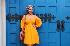 a cool off the shoulder yellow knee dress with puff sleeves, metallic sandals and a brown bag